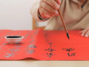 Person doing calligraphy on orange paper
