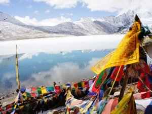 Colourful prayer flags on hillside overlooking lake