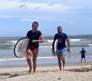 People walking on beach holding surfboards