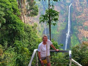 Woman standing infront of tall waterfall