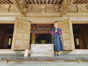 Man standing with hands in a prayer outside of temple