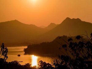 Silhouette of mountains and a river at sunset orange skies