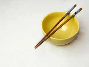 Chopsticks over small yellow bowl