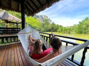 Mother and daughter on a hammock beside a river in Thailand