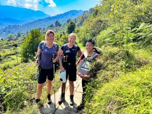 Tourists hiking in green foothills of Nepal with local guide