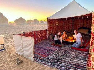 People gathered around a table in a desert camp