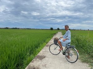 Woman cycling through green rice fields