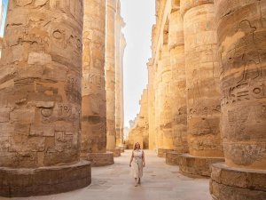 Woman walking through columns at Karnak Temple in Luxor