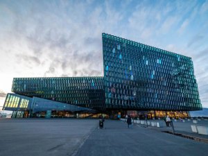 A large modern building with a shimmering geometric glass façade stands on a wide plaza in Reykjavik in Iceland.