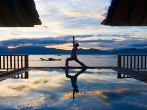Person practicing yoga near infinity pool