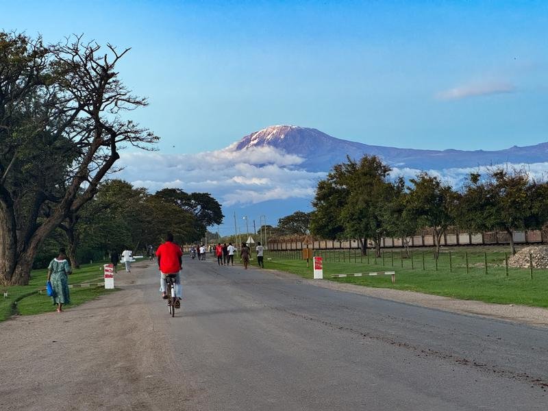People cycling on path with Mt Kilimanjaro in the distance