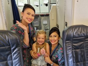 Young girl on plane with cabin crew