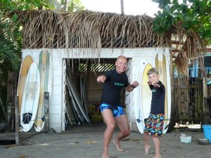 Man and boy practising surfing position on the beach