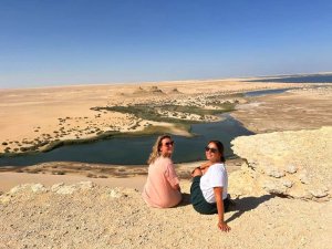 women posing in front of water in the desert 