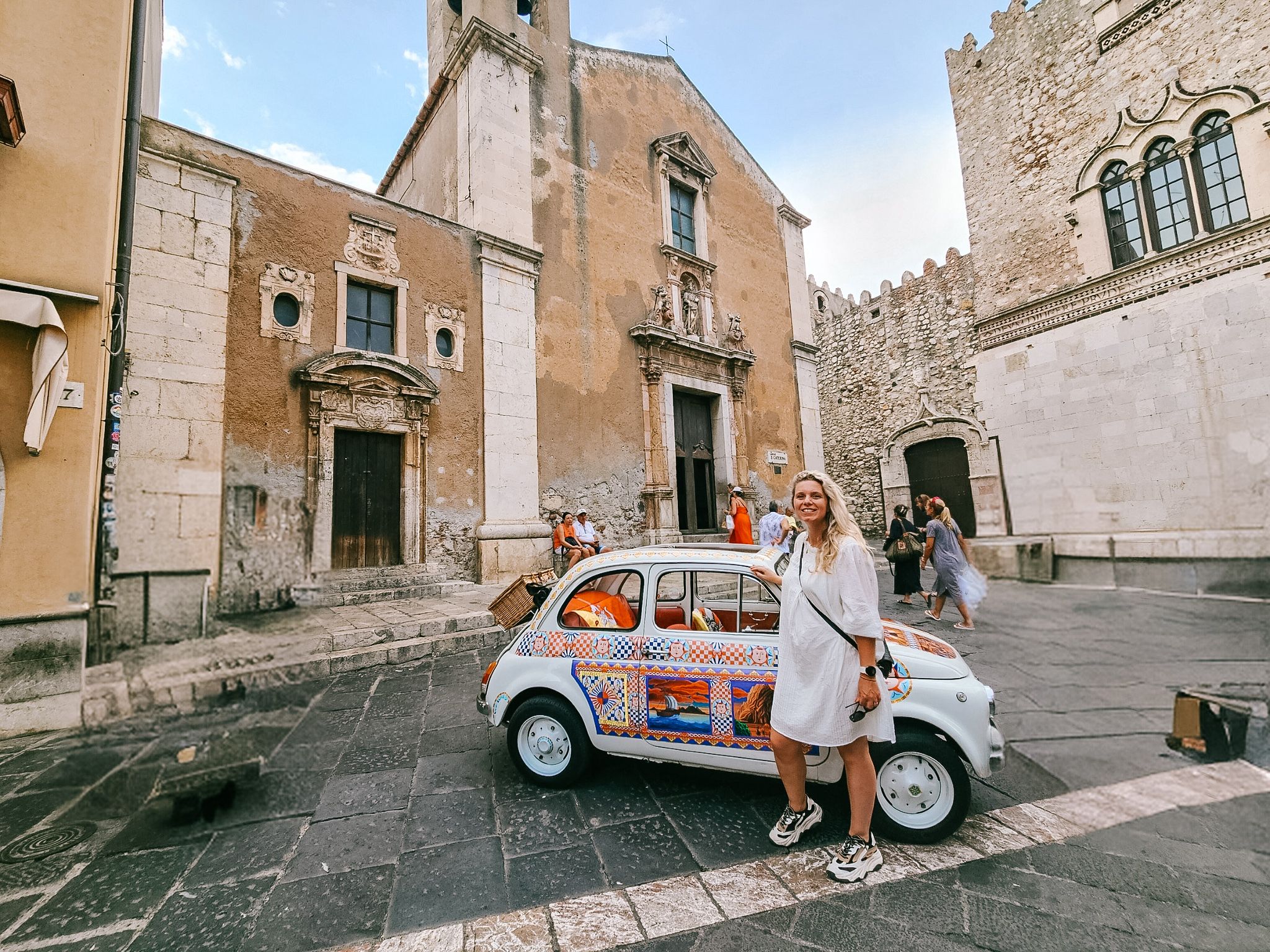 Woman standing in old street with old colourful car