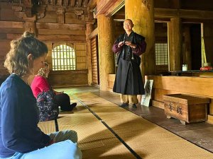 Woman meditating while being guided by a monk