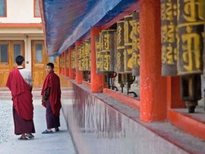 Two monks standing beside prayer wheels in India