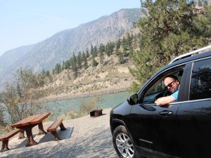 Man in car in front of river in Canada