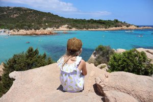 Child sitting on rock looking out to sea