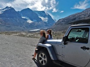 women by car in front of mountain