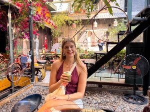 Girl sitting outside in colourful setting holding a coffee