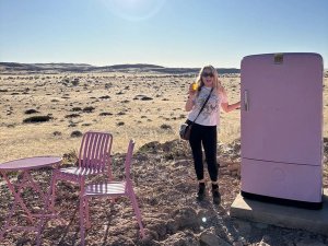 Gemma standing next the pink fridge in the desert in Namibia