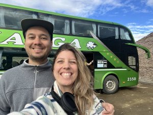 Couple smiling by a big green bus