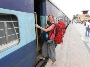 Woman stepping onto a train wearing red backpack