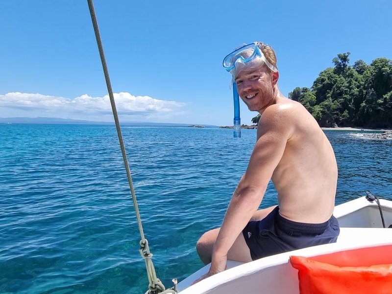 Man sat on edge of boat wearing snorkelling mask on head
