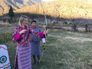 Tourist in Bhutanese traditional dress trying archery