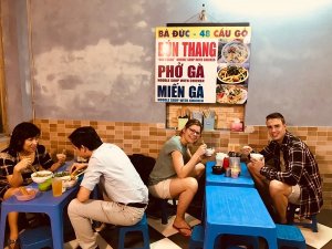 Travellers sat on stools enjoying a local meal