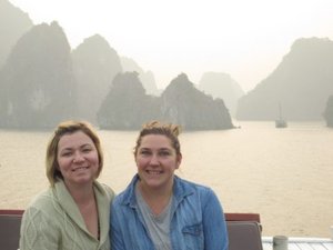 Two women smiling at camera with limestone cliffs and water behind them